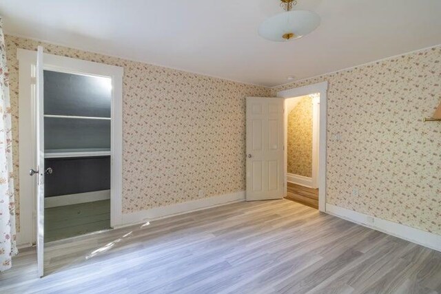 753 Sebec Village Rd, Sebec, ME 04481 - unfurnished bedroom with wood finished floors, wallpapered walls, and baseboards