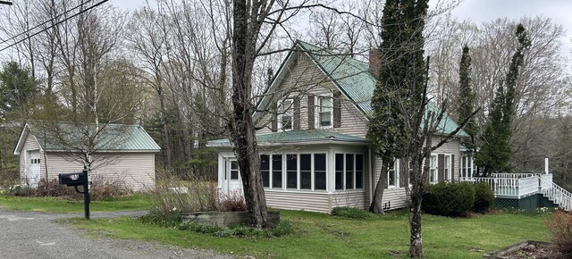 753 Sebec Village Rd, Sebec, ME 04481 - view of front of property with a chimney, a front yard, a deck, and a sunroom