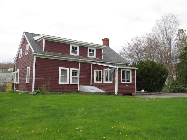 rear view of house featuring a yard, roof with shingles, and a chimney