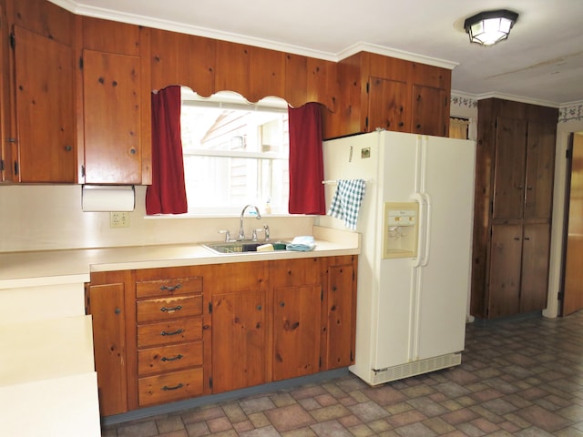 kitchen featuring a sink, crown molding, light countertops, white refrigerator with ice dispenser, and brick patterned floor