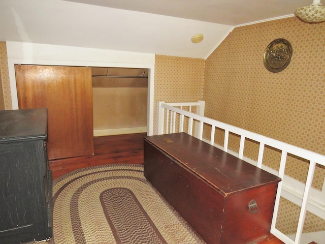 corridor with wallpapered walls, dark wood finished floors, and vaulted ceiling