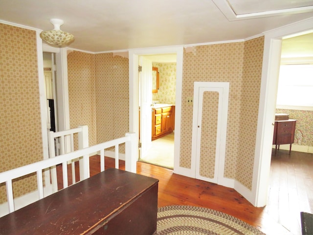 hall featuring hardwood / wood-style floors, crown molding, and wallpapered walls