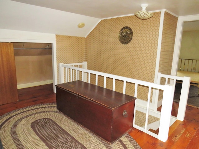 interior space with ornamental molding, wallpapered walls, lofted ceiling, and wood-type flooring