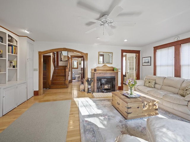 living area featuring arched walkways, a ceiling fan, light wood-style floors, stairs, and recessed lighting