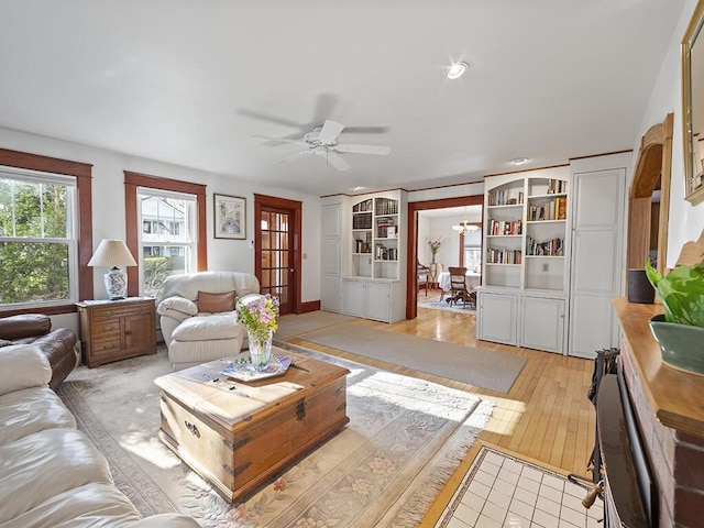 living area featuring a ceiling fan, built in shelves, light wood finished floors, and recessed lighting
