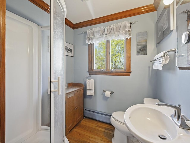 full bath featuring baseboard heating, a sink, a shower stall, wood finished floors, and crown molding