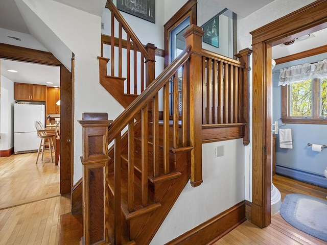 stairs with wood-type flooring, baseboards, and a baseboard heating unit