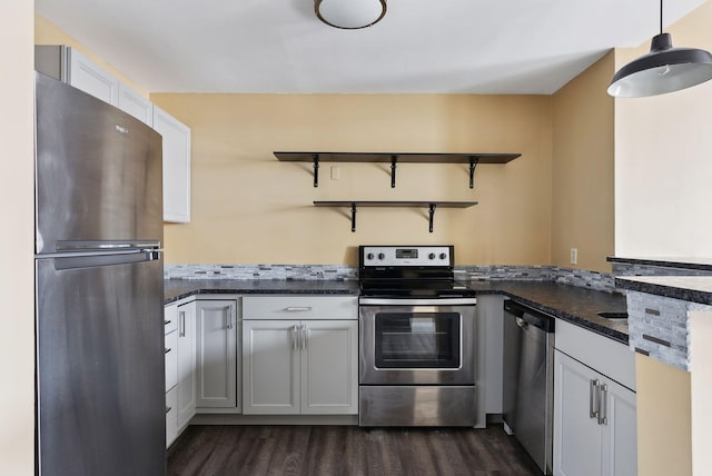 kitchen featuring appliances with stainless steel finishes, open shelves, dark wood-style flooring, hanging light fixtures, and a peninsula