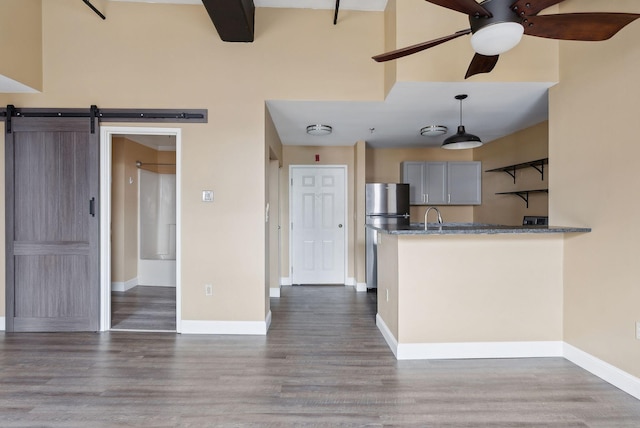 kitchen featuring a ceiling fan, freestanding refrigerator, dark wood finished floors, and baseboards