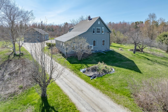 view of home's exterior featuring a chimney, driveway, and a yard