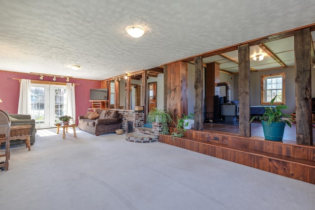 carpeted living area with a wood stove, a textured ceiling, and a healthy amount of sunlight