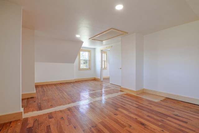 additional living space with recessed lighting, attic access, baseboards, and hardwood / wood-style flooring