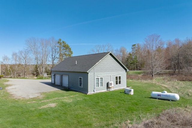 rear view of house with a garage, a shingled roof, and a lawn