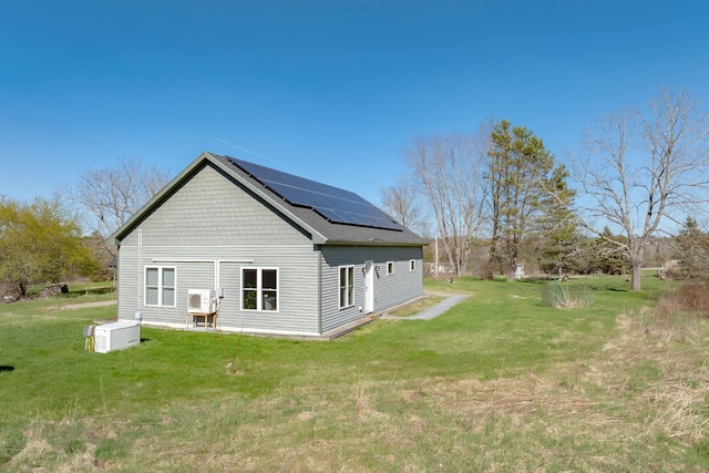 rear view of house with a yard and solar panels