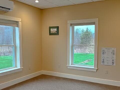 carpeted spare room featuring baseboards and a wall mounted AC