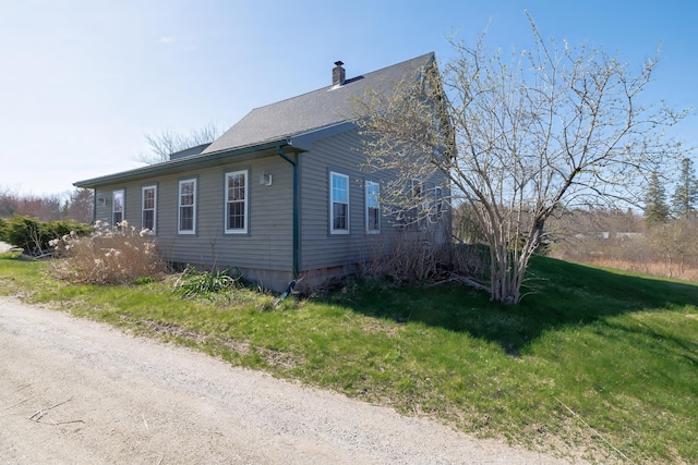 view of home's exterior featuring a chimney and a yard