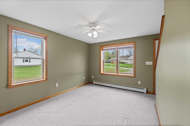 carpeted spare room featuring a baseboard heating unit, ceiling fan, and baseboards