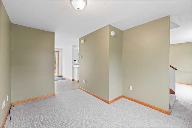 spare room featuring carpet and baseboards