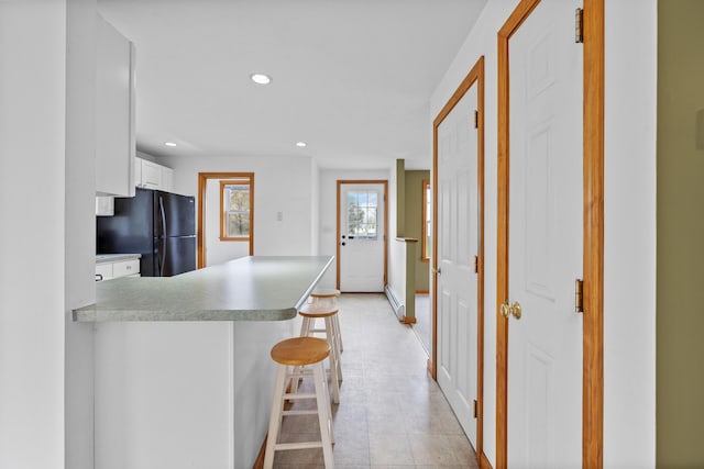 kitchen featuring freestanding refrigerator, baseboard heating, recessed lighting, a peninsula, and white cabinets