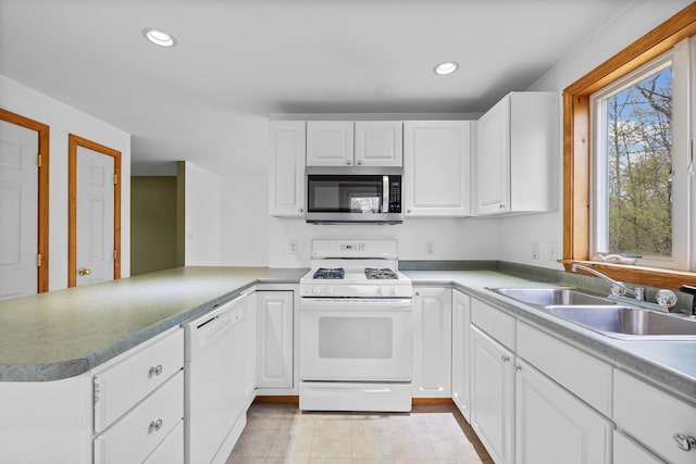 kitchen featuring white appliances, a sink, a peninsula, white cabinetry, and recessed lighting
