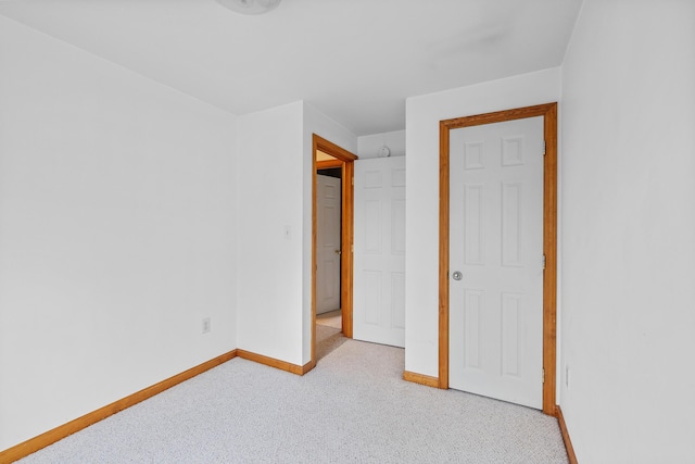 unfurnished bedroom featuring light carpet and baseboards