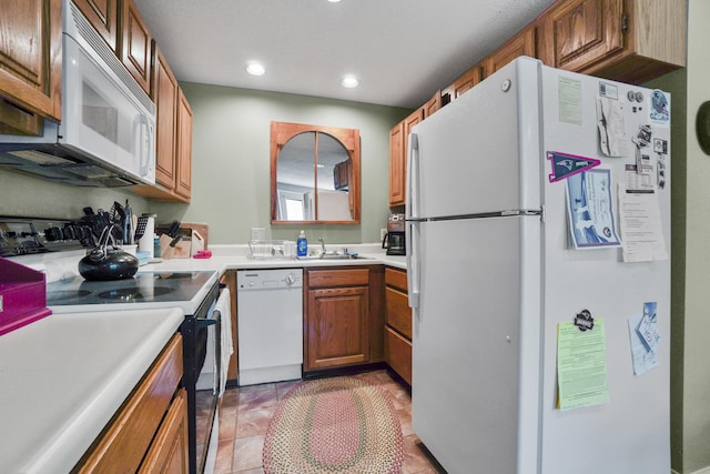 kitchen with white appliances, recessed lighting, brown cabinetry, a sink, and light countertops