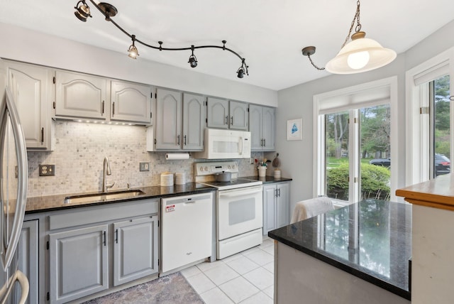 kitchen featuring white appliances, a sink, backsplash, gray cabinets, and light tile patterned floors