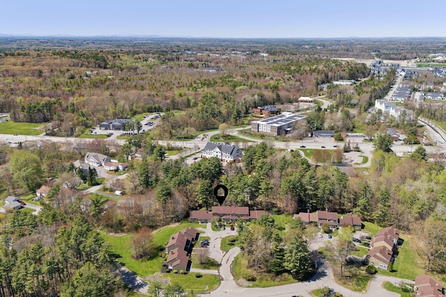 aerial view of property and surrounding area featuring a forest and nearby suburban area