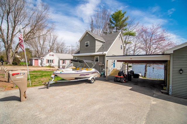 view of front facade with driveway, a carport, and a shingled roof