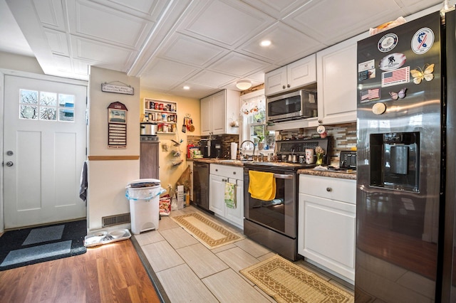 kitchen with stainless steel appliances, white cabinetry, tasteful backsplash, light wood-style flooring, and recessed lighting