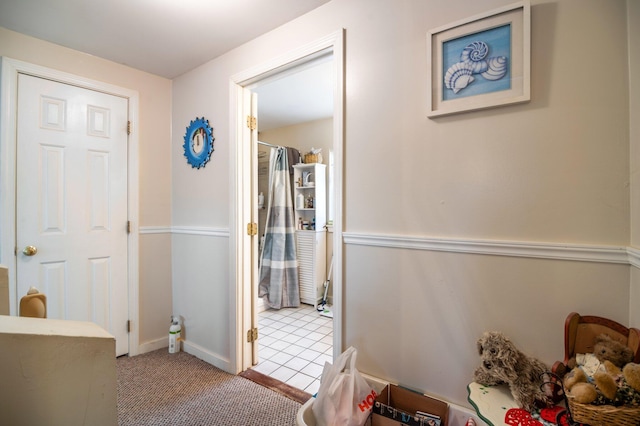 corridor with baseboards, carpet floors, and tile patterned flooring