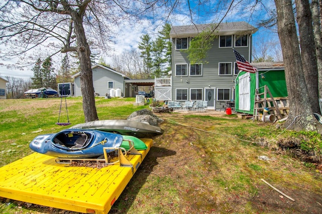 rear view of property featuring a storage shed, a lawn, an outbuilding, and a patio