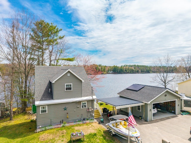 view of front of property with a water view, asphalt driveway, roof with shingles, a carport, and solar panels