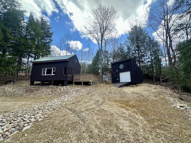 42 Cyrs Siding Rd, Saint Albans, ME 04971 - view of front of home with an outdoor structure, a wooden deck, dirt driveway, metal roof, and a garage