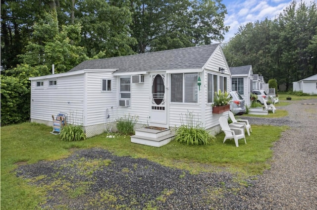 76 Post Rd Unit C9, Wells, ME 04090 - view of front of property featuring a shingled roof, a wall mounted air conditioner, a front lawn, and view of scattered trees