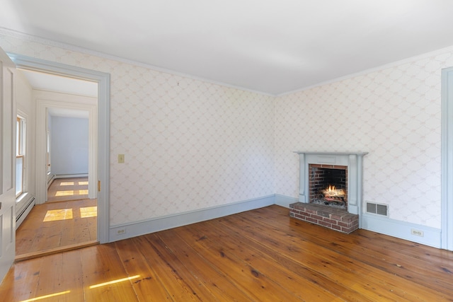 44 Pascal Ave, Rockport, ME 04856 - unfurnished living room with wood-type flooring, a baseboard radiator, wallpapered walls, crown molding, and a brick fireplace