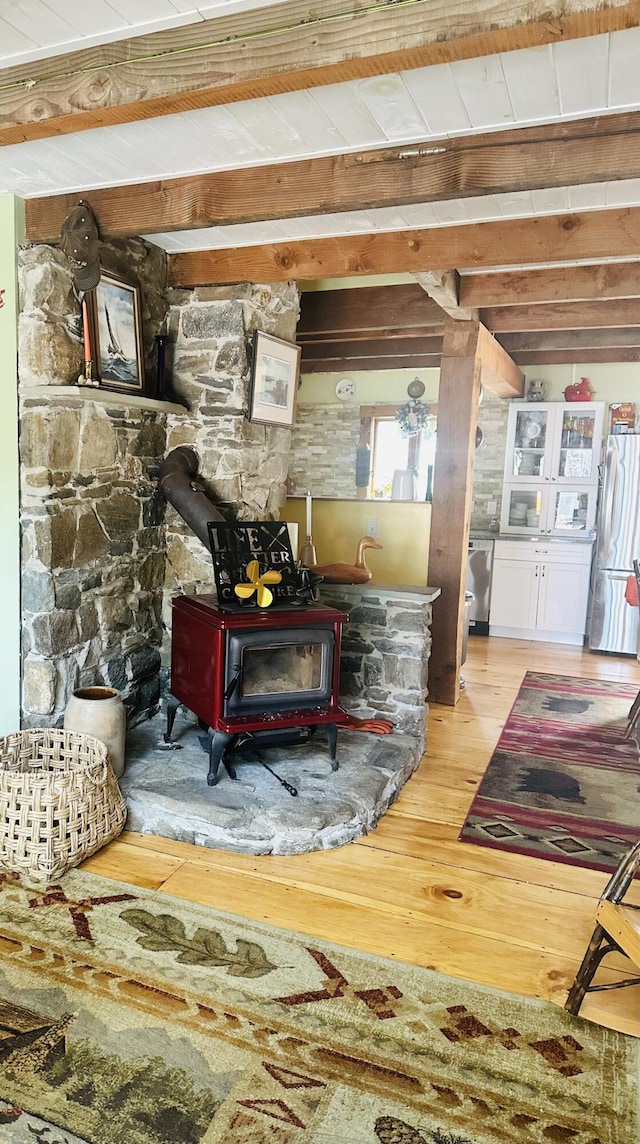 1363 Hallowell Rd, Litchfield, ME 04350 - detailed view of a wood stove, wood finished floors, beamed ceiling, and freestanding refrigerator