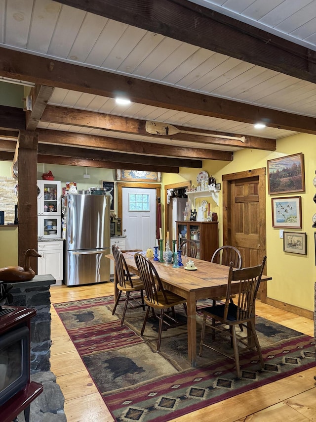 1363 Hallowell Rd, Litchfield, ME 04350 - dining space with light wood-style floors, beamed ceiling, wooden ceiling, and a wood stove