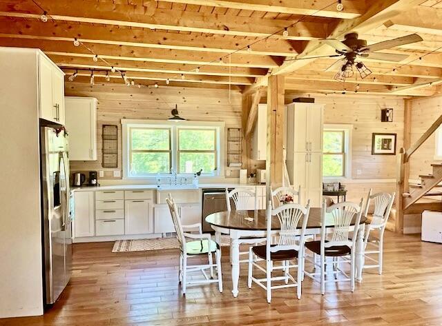 26 Hamilton Dr, Vinalhaven, ME 04863 - dining room with beamed ceiling, wood walls, light wood finished floors, stairs, and a ceiling fan