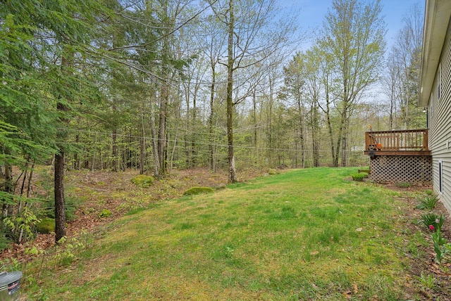 view of green lawn with a deck and a view of trees