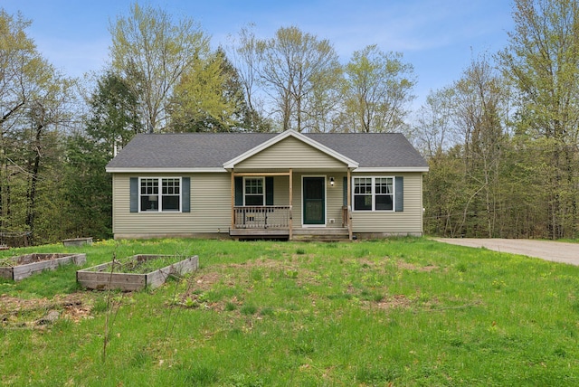 ranch-style home featuring covered porch, a vegetable garden, a front yard, and a shingled roof