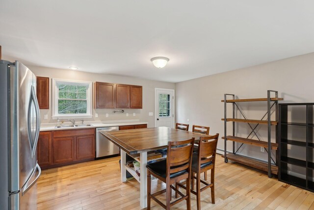 kitchen featuring stainless steel appliances, a sink, light wood finished floors, and light countertops