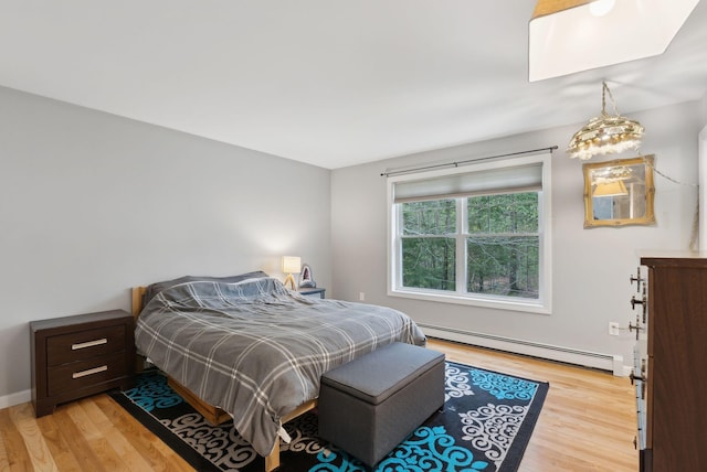 bedroom with a baseboard radiator and light wood finished floors