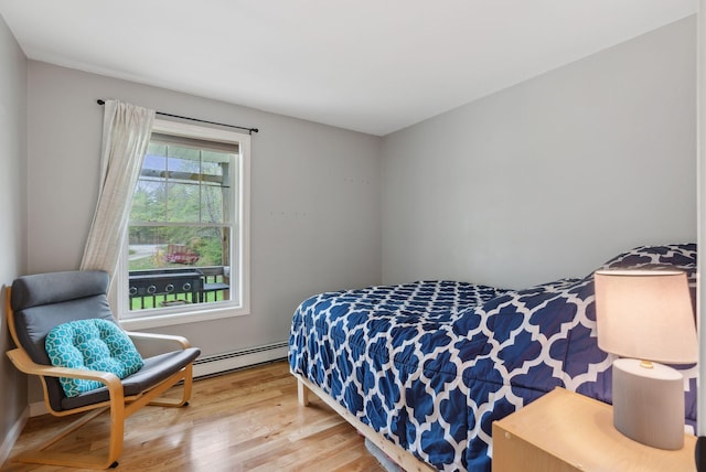 bedroom with baseboard heating and wood finished floors