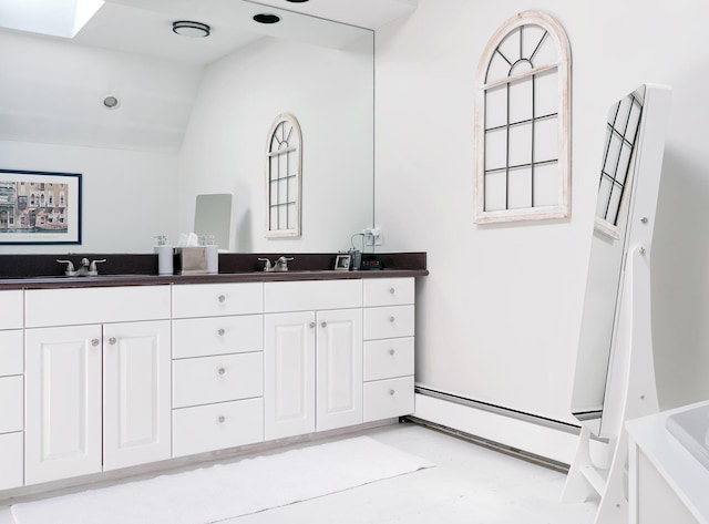 63 Fletcher St, Kennebunk, ME 04043 - bathroom featuring a baseboard heating unit, double vanity, vaulted ceiling, and a tub