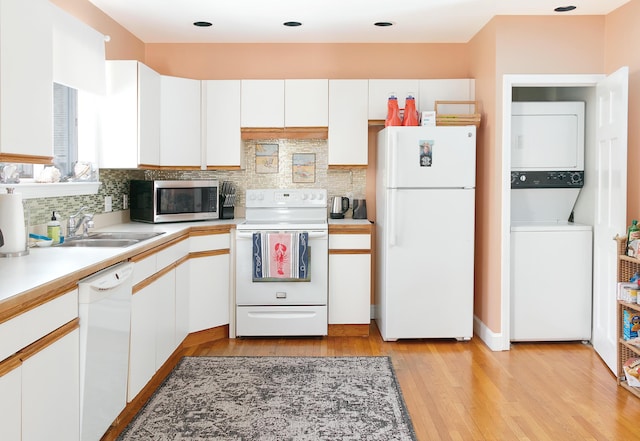 63 Fletcher St, Kennebunk, ME 04043 - kitchen with white appliances, stacked washer / dryer, a sink, light wood-style flooring, and white cabinetry