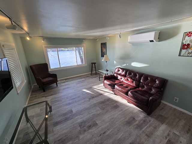 living room with rail lighting, baseboards, a wall mounted air conditioner, and wood finished floors