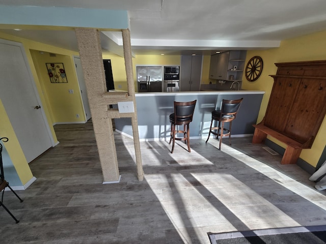 kitchen featuring baseboards, a kitchen breakfast bar, open shelves, and appliances with stainless steel finishes