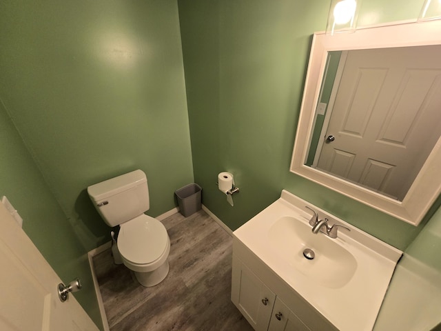 bathroom with vanity, toilet, baseboards, and wood finished floors