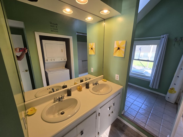 bathroom with double vanity, stacked washing maching and dryer, and a sink